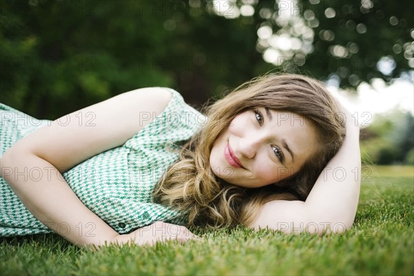 Portrait of woman lying on grass and smiling