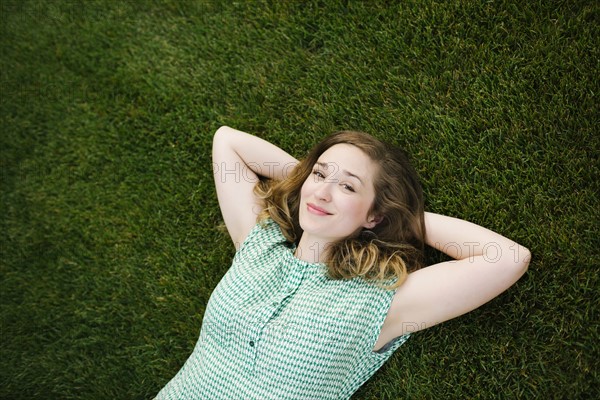 Portrait of woman lying on grass and looking at camera