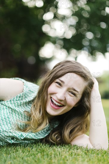 Portrait of woman lying on grass and laughing