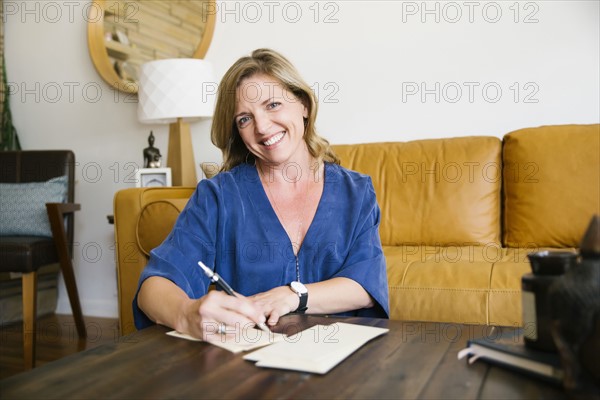 Portrait of woman writing letter in living room