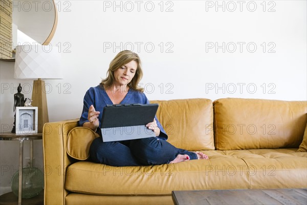 Woman using digital tablet on sofa