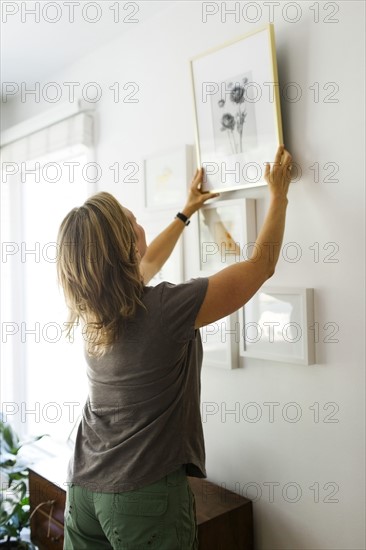 Woman hanging picture frames on wall
