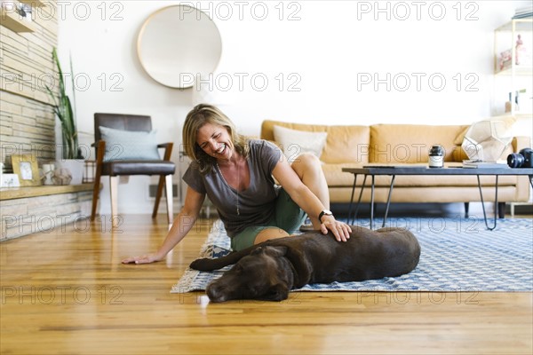 Woman stroking Labrador Retriever in living room