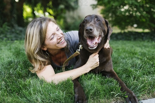 Smiling woman lying on grass with Labrador Retriever