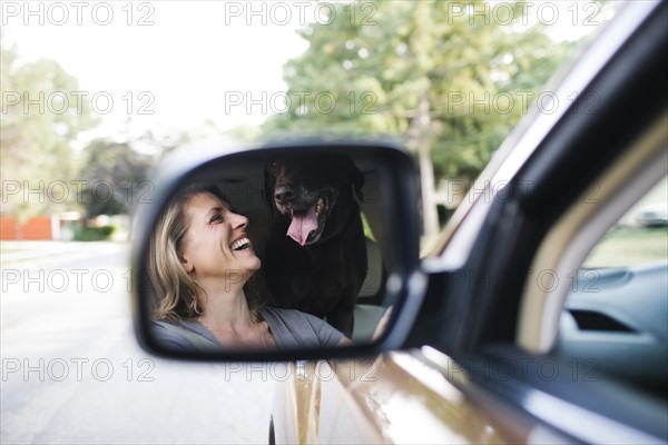 Woman and Labrador Retriever reflecting in side-view mirror