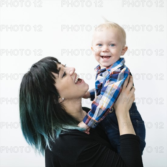 Portrait of mother holding son (12-17 months) against white background