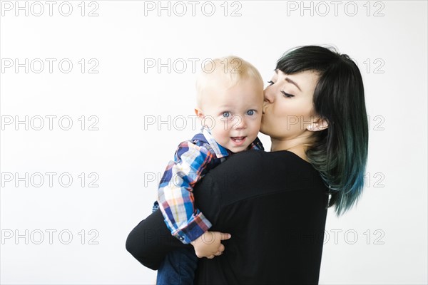 Portrait of mother kissing son (12-17 months) against white background