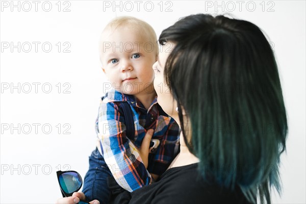 Portrait of mother holding son (12-17 months) against white background