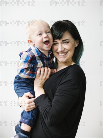 Portrait of mother holding son (12-17 months) against white background