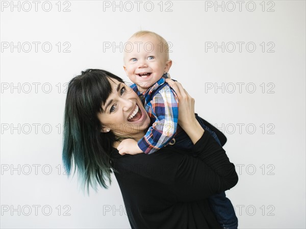 Portrait of mother holding son (12-17 months) against white background