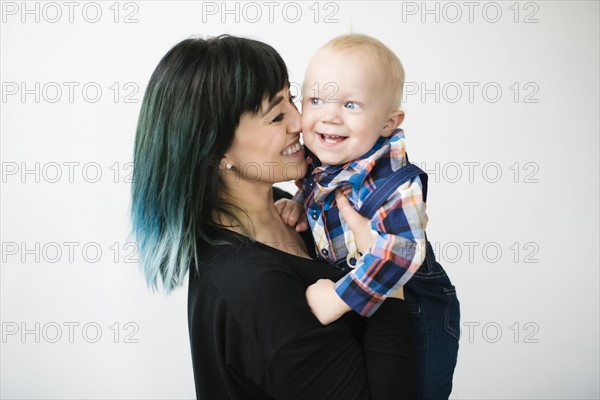 Portrait of mother holding son (12-17 months) against white background