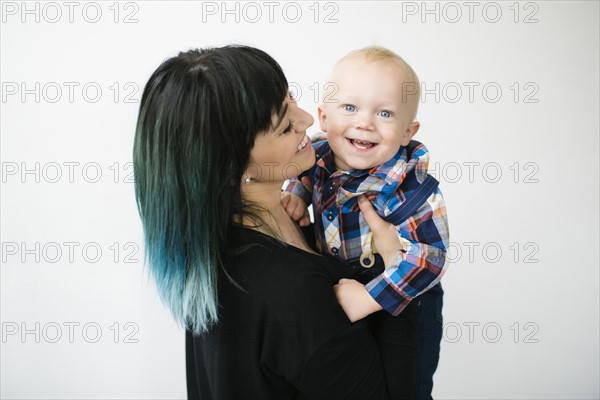 Portrait of mother holding son (12-17 months) against white background