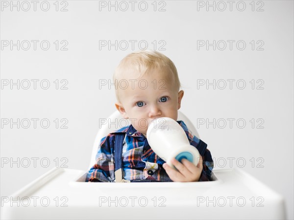 Studio shot of boy (12-17 months) drinking from baby bottle