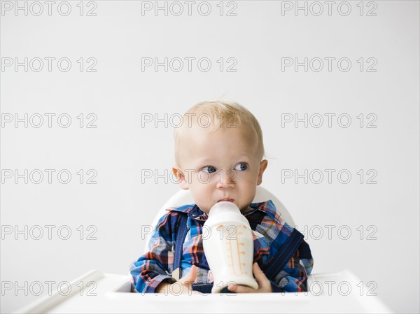 Studio shot of boy (12-17 months) drinking from baby bottle