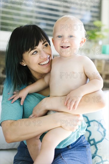 Mother carrying baby boy (12-17 months) on porch