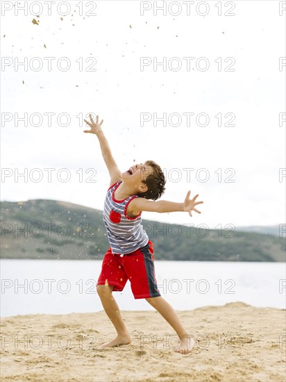 Boy (6-7) playing on beach by lake