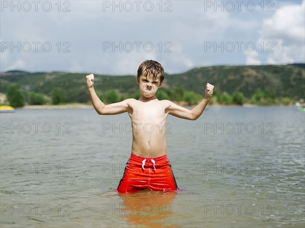 USA, Utah, Park City, Boy (6-7) flexing muscles while wading in lake