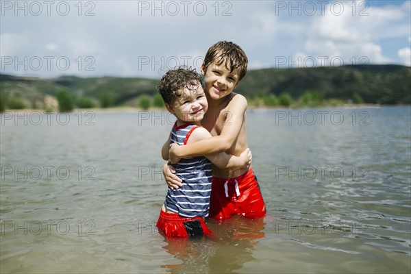 USA, Utah, Park City, Brothers (4-5, 6-7) embracing in lake