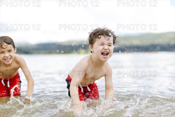 Brothers (4-5, 6-7) splashing water in lake