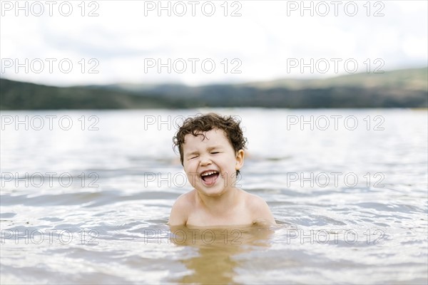 Smiling boy ( 4-5) swimming in lake