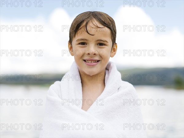 Portrait of boy (6-7) wrapped in towel by lake