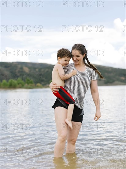 USA, Utah, Park City, Mother carrying son (4-5) while wading in lake