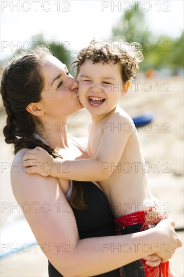 Mother kissing son (4-5) on beach