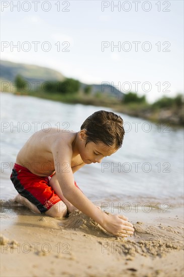 Boy (6-7) playing on beach by lake