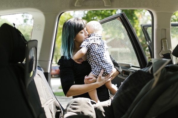 Mother carrying baby boy ( 12-17 months ) into car