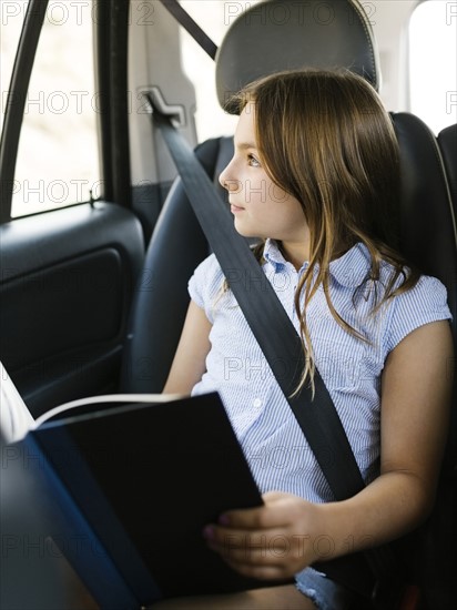 Girl ( 8-9) sitting in car and looking through window