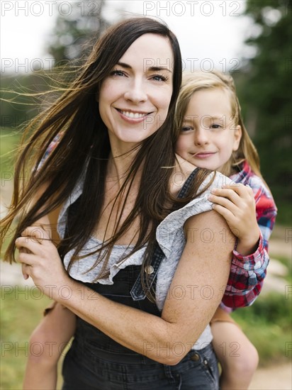 Outdoor portrait of mother playing carrying son (6-7)