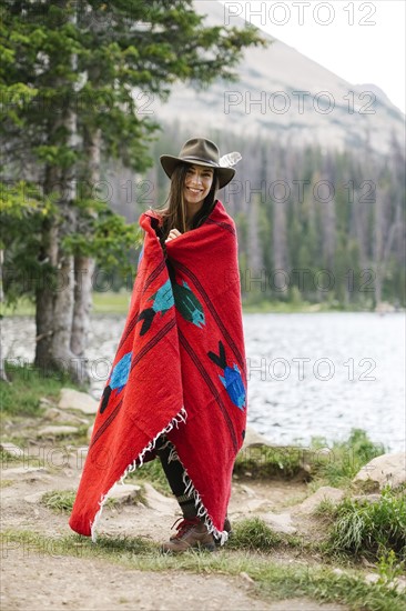 USA, Utah, Midway, Portrait of woman wearing hat and wrapped in blanket while standing by lake