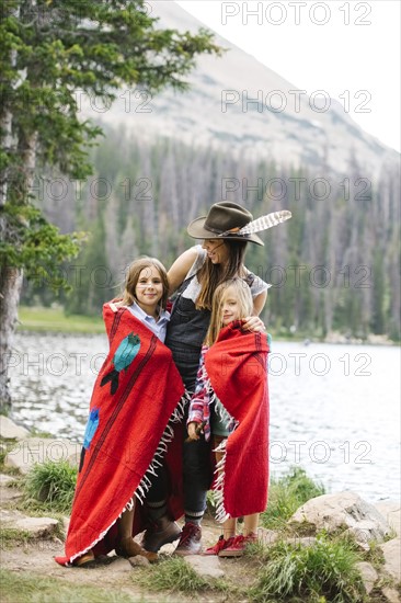 Mother with kids (6-7, 8-9) wrapped in blanket standing by lake