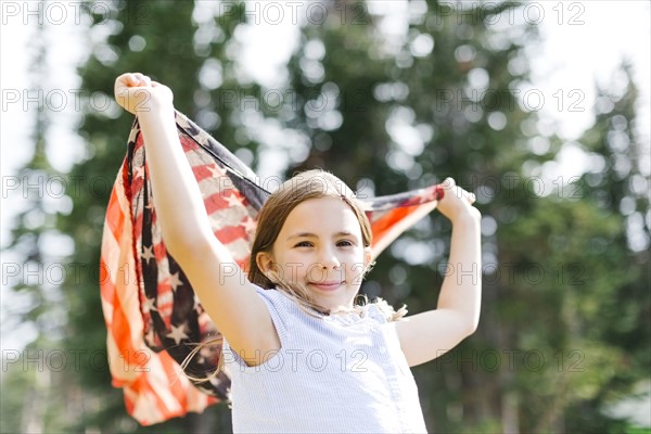 Girl (8-9) holding us flag in forest