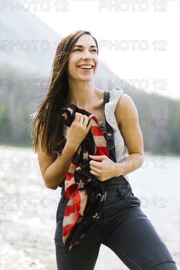 Portrait of woman holding us flag by lake