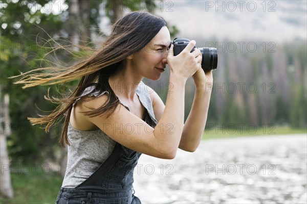 Woman taking pictures by lake