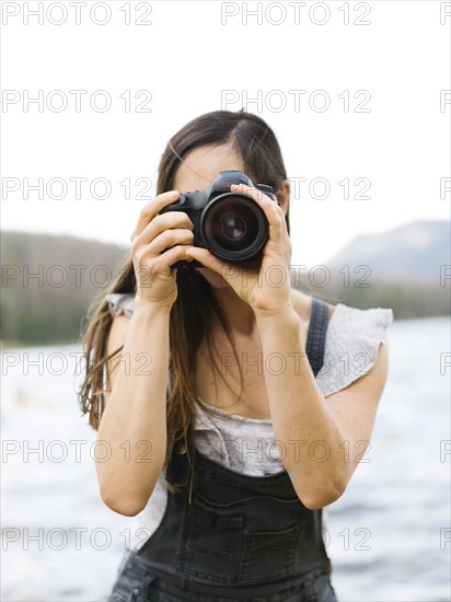 Woman taking pictures by lake