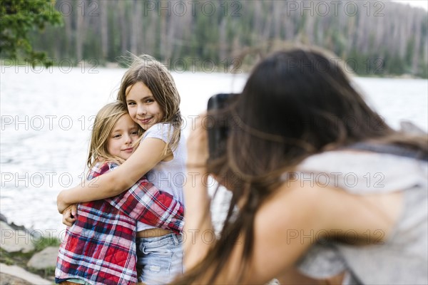 Mother taking pictures of son (6-7) and daughter (8-9) by lake