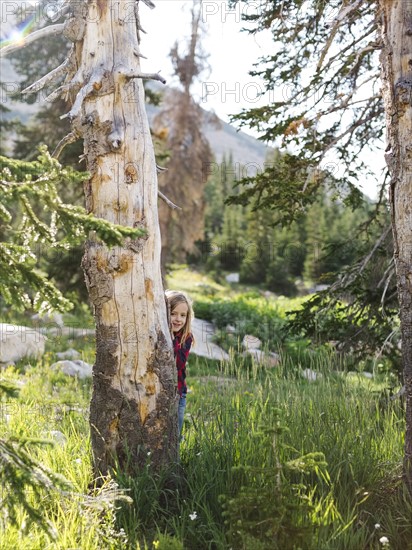 Boy (6-7) hiding behind tree