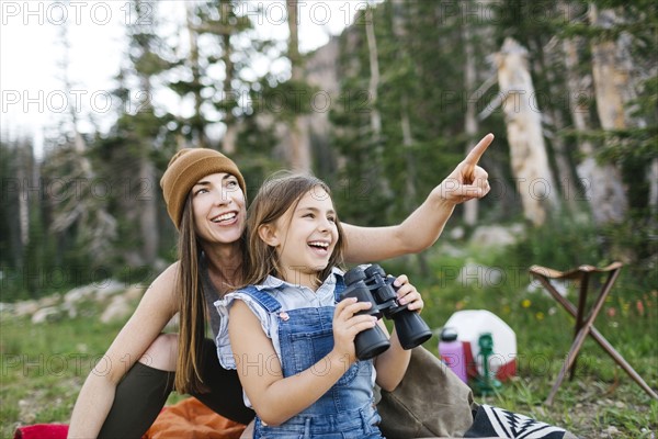 Mother with daughter (8-9) using binoculars in forest