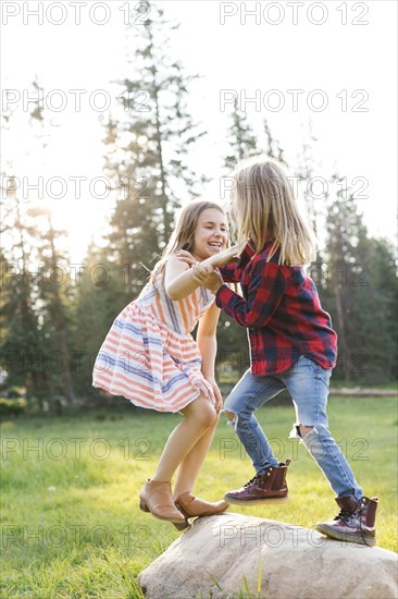 Boy (6-7) and girl (8-9) play-fighting in forest