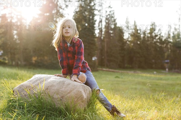 Portrait of boy (6-7) sitting on rock in forest