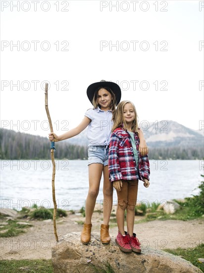 Girl (8-9) and boy (6-7) standing at lakeshore