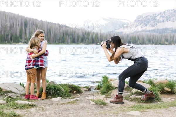 Mother photographing girl (8-9) and boy (6-7) by lake