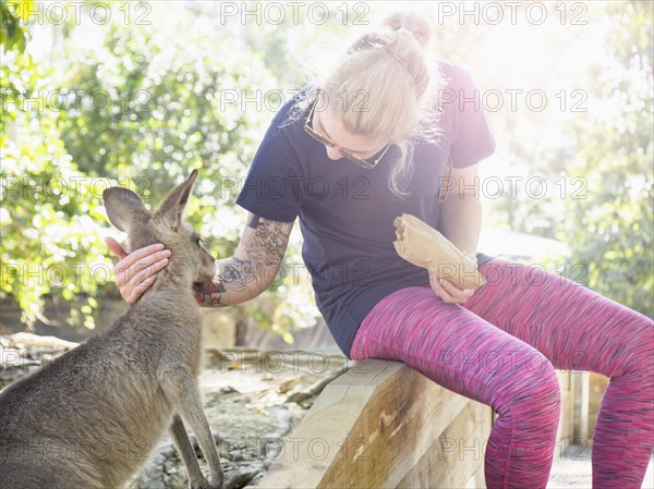 Young woman stroking Eastern grey kangaroo (Macropus giganteus)