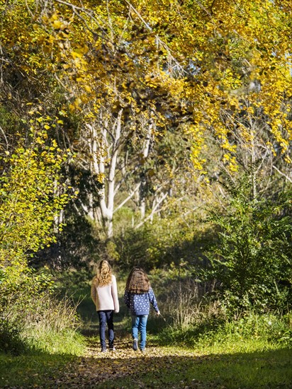 Australia, Queensland, Girls (10-11, 12-13) walking on footpath at autumn