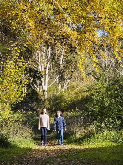 Australia, Queensland, Girls (10-11, 12-13) walking on footpath at autumn