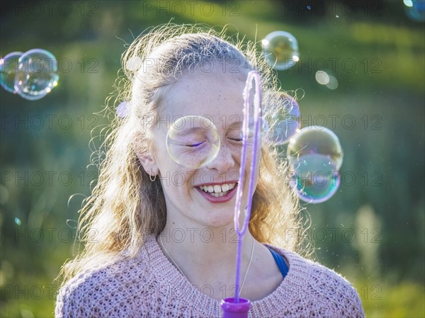 Girl (12-13) blowing bubbles