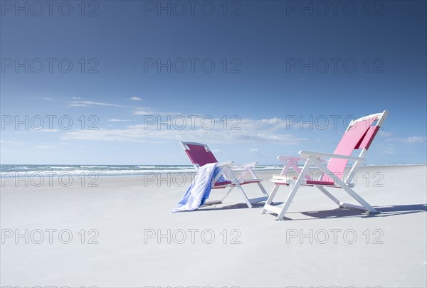 Two deckchairs on empty beach