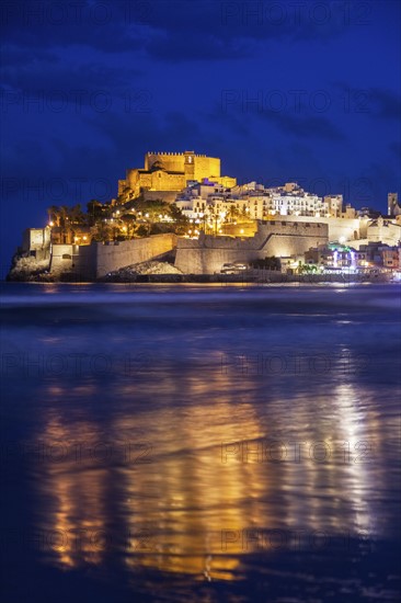 Spain, Valencian Community, Peniscola, Town with fortified wall by sea at dusk